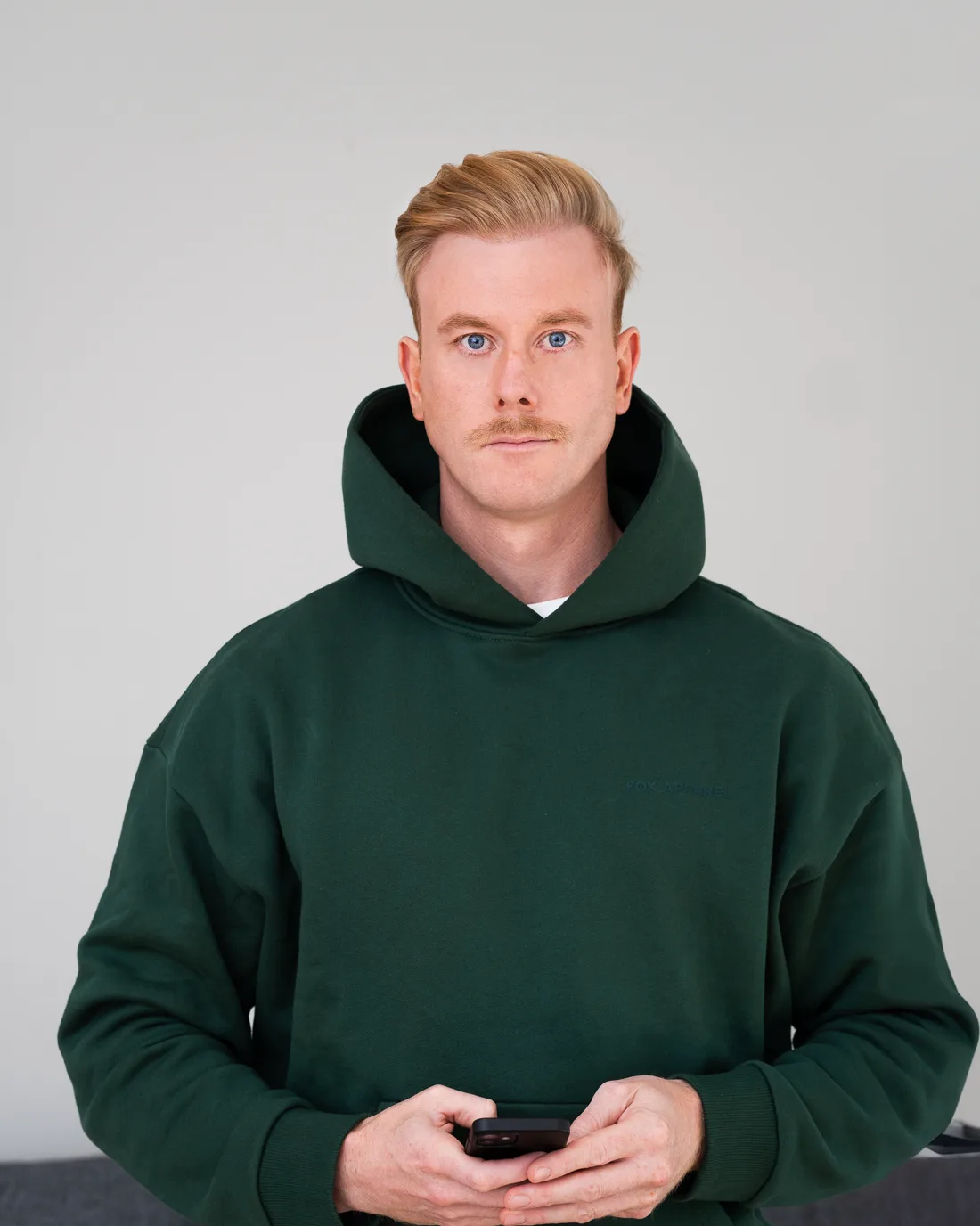 Sebastian Fernströning im dunkelgrünen Hoodie, das Smartphone in der Hand